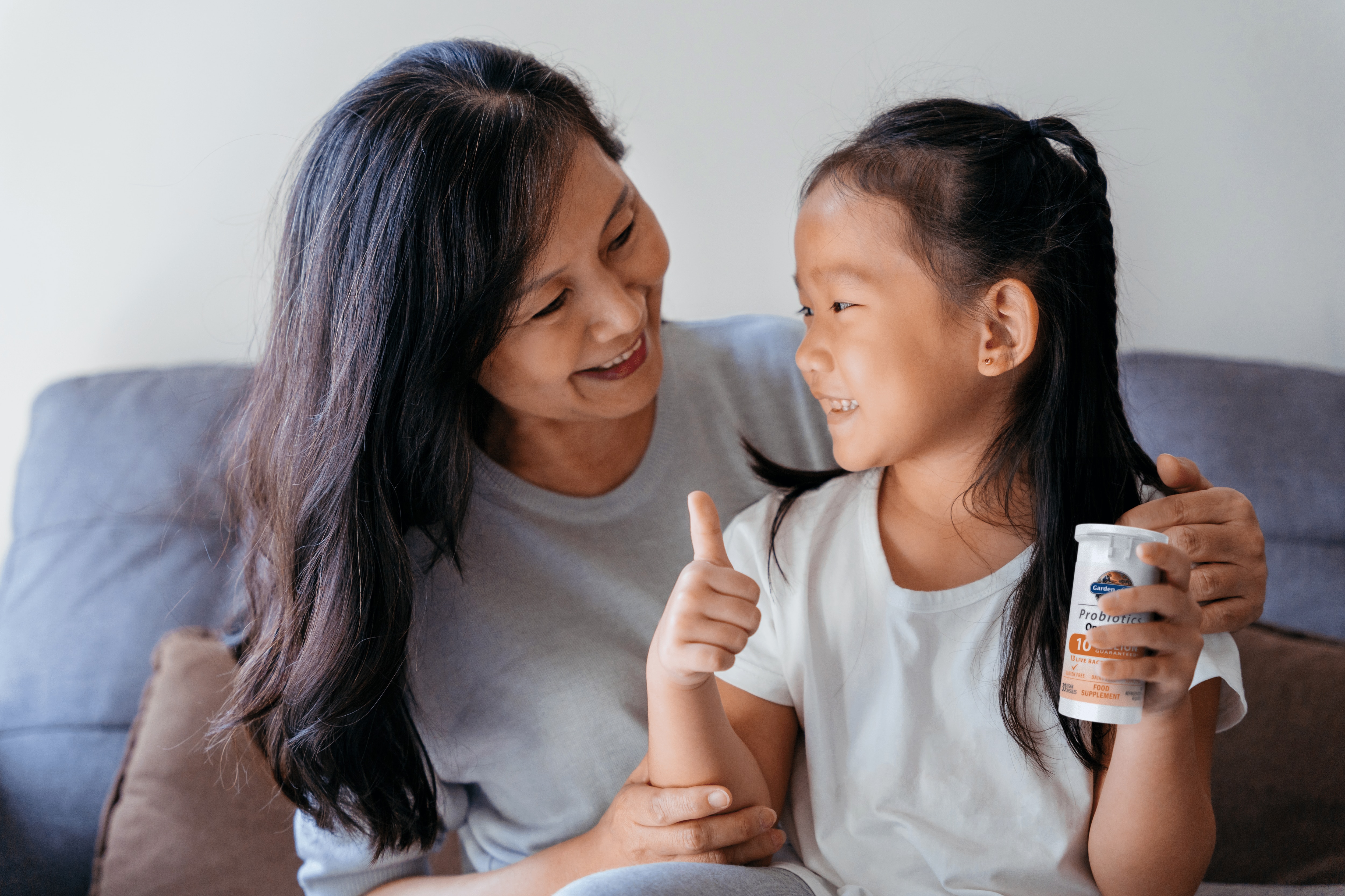 A joyful woman and her smiling daughter holding a Garden of Life product, embodying family wellness and natural health solutions.